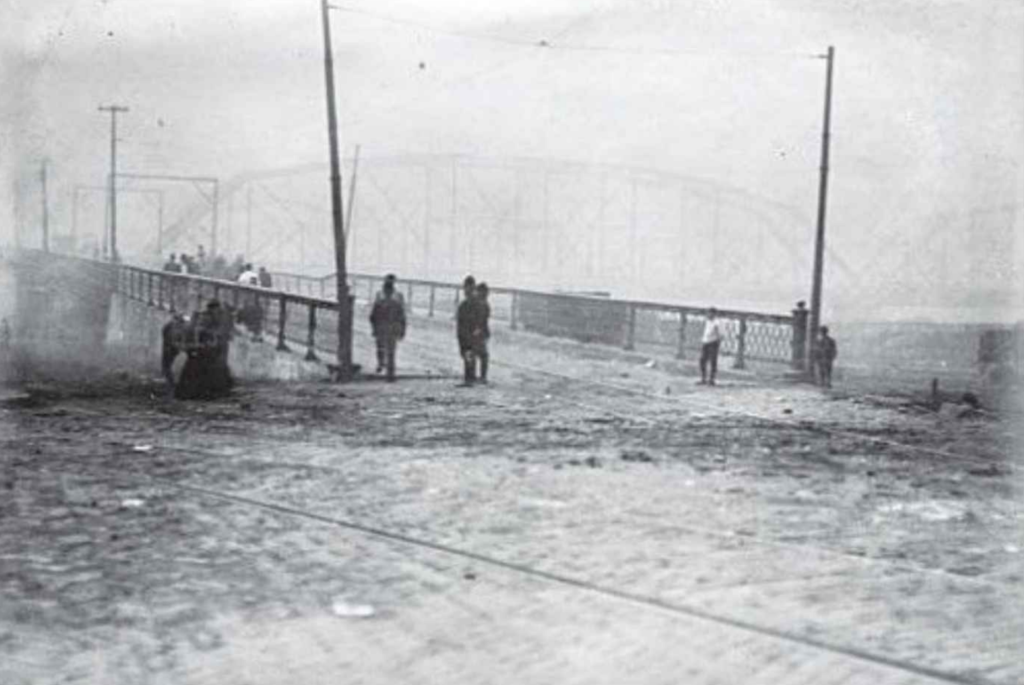 A distant photo of a bridge with about five people at the front of it.